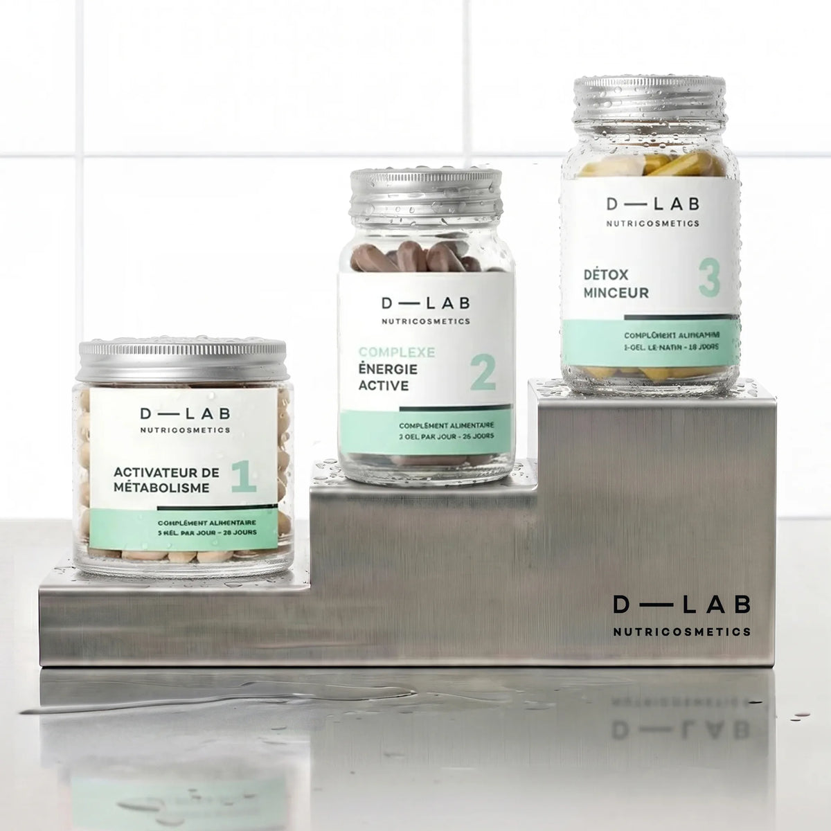 Routine Brûle-Graisses D-LAB cure 1 mois, les trois pots Activateur de Métabolisme, Complexe Énergie Active et Détox Minceur disposés en escalier sur socles inox
